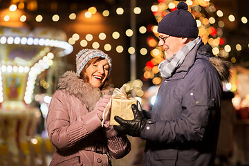 Image showing happy senior couple with gift at christmas market