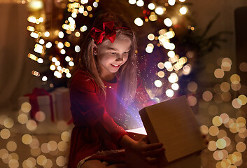 Image showing smiling girl opening christmas gift at night