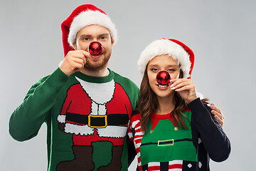 Image showing happy couple in christmas sweaters and santa hats