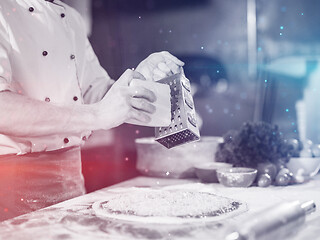 Image showing chef sprinkling cheese over fresh pizza dough