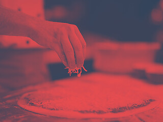 Image showing chef sprinkling cheese over fresh pizza dough