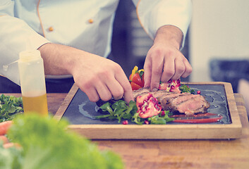 Image showing closeup of Chef hands serving beef steak