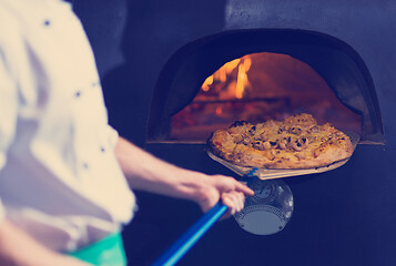 Image showing chef removing hot pizza from stove