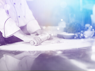 Image showing chef preparing dough for pizza with rolling pin