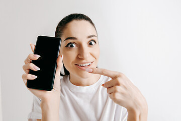 Image showing Portrait of a confident casual girl showing blank screen of mobile phone