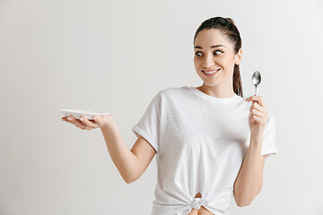 Image showing Young fun crazy brunette housewife with spoon isolated on white background