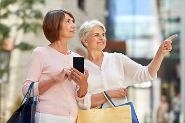 Image showing old women with shopping bags and cellphone in city