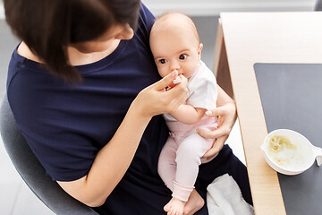 Image showing middle-aged mother feeding baby daughter at home