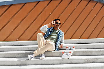 Image showing indian man with skateboard sitting on city stairs