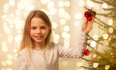 Image showing happy girl in red dress decorating christmas tree