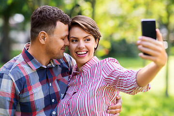 Image showing happy couple in park taking selfie by smartphone