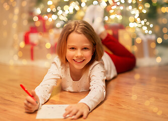 Image showing smiling girl writing christmas wish list at home