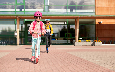 Image showing happy school children riding scooters outdoors