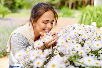 Image showing happy woman smelling chamomile flowers in garden