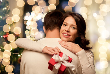 Image showing happy couple with christmas gift hugging at home