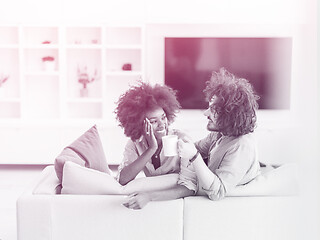 Image showing multiethnic couple sitting on sofa at home drinking coffe