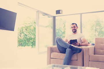 Image showing young man using a tablet at home