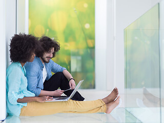 Image showing multiethnic couple using a laptop on the floor