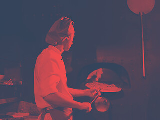 Image showing chef putting delicious pizza to brick wood oven