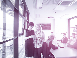 Image showing Two Elegant Women Using Mobile Phone by window in office buildin