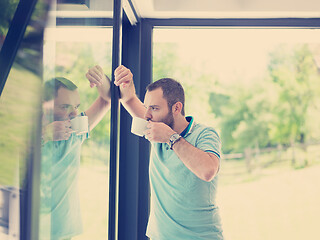 Image showing young man drinking morning coffee by the window