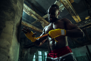 Image showing Afro American boxer is wrapping hands with bandage