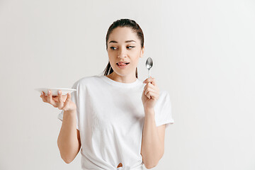 Image showing Young fun crazy brunette housewife with spoon isolated on white background