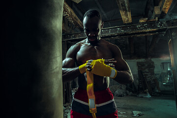 Image showing Afro American boxer is wrapping hands with bandage