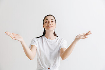 Image showing The happy woman standing and smiling against gray background.