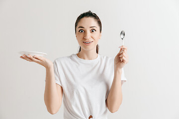 Image showing Young fun crazy brunette housewife with spoon isolated on white background