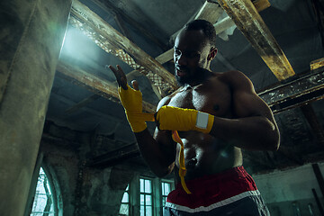 Image showing Afro American boxer is wrapping hands with bandage