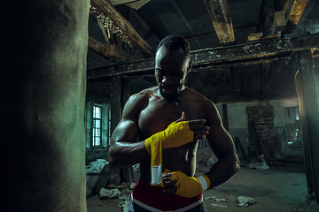 Image showing Afro American boxer is wrapping hands with bandage