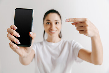 Image showing Portrait of a confident casual girl showing blank screen of mobile phone