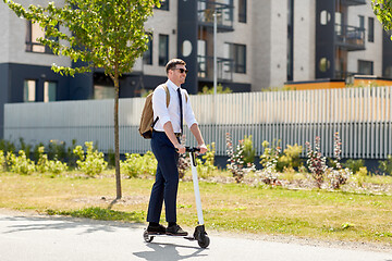 Image showing businessman with backpack riding electric scooter