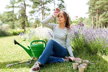 Image showing tired young woman with garden tools in summer