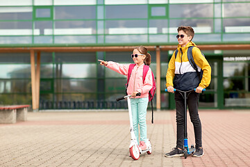 Image showing happy school children with backpacks and scooters