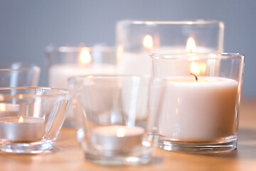 Image showing burning white fragrance candles on wooden table