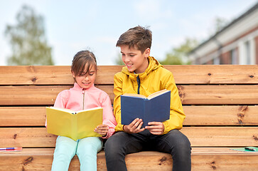 Image showing school children reading books sitting on bench