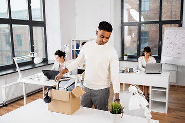 Image showing sad fired office worker packing personal stuff