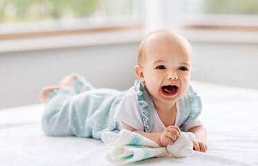 Image showing crying baby girl lying on white blanket