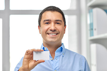 Image showing smiling businessman with business card at office