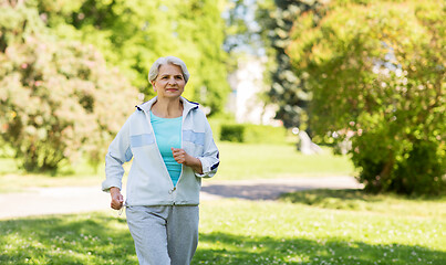 Image showing senior woman running along summer park