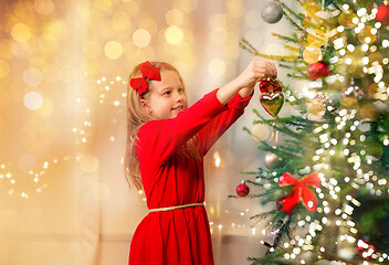 Image showing happy girl in red dress decorating christmas tree
