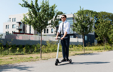 Image showing young businessman riding electric scooter outdoors