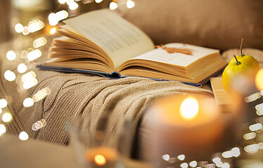 Image showing book with autumn leaf and blanket on sofa at home