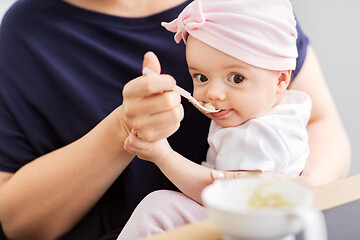 Image showing middle-aged mother feeding baby daughter at home