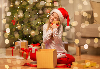 Image showing smiling girl in santa hat with christmas gift