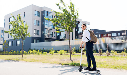 Image showing businessman with backpack riding electric scooter