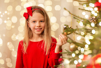 Image showing happy girl in red decorating christmas tree