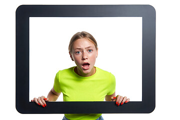 Image showing Indignant girl peeking through digital tablet frame